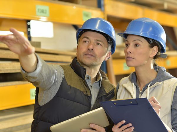 Worker with overseer controling stock in warehouse